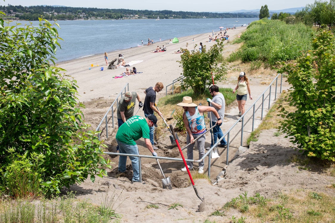 A group of volunteers using shovels to clean an access ramp of sand