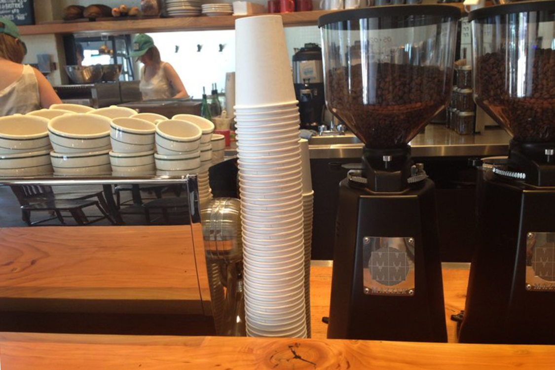 a stack of paper coffee cups at the counter of a coffee shop