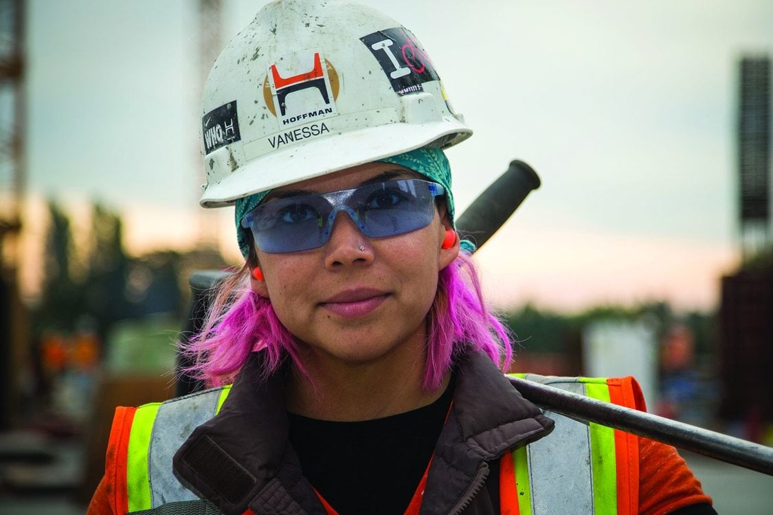 Photo of a woman wearing a hard hat and vest on a construction site