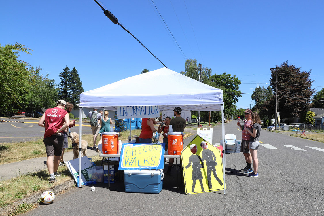 Volunteer organizers under a tent, where water coolers sit on a table.