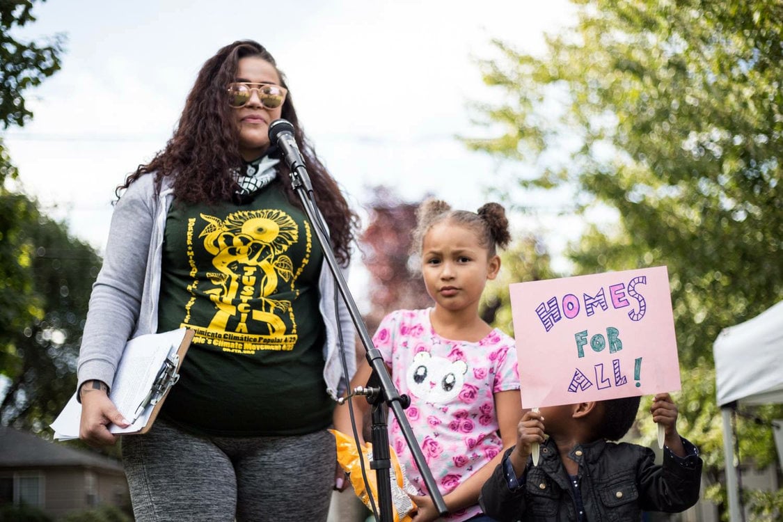 A child holds a sign that reads, "Homes for All" at a rally for tenant rights