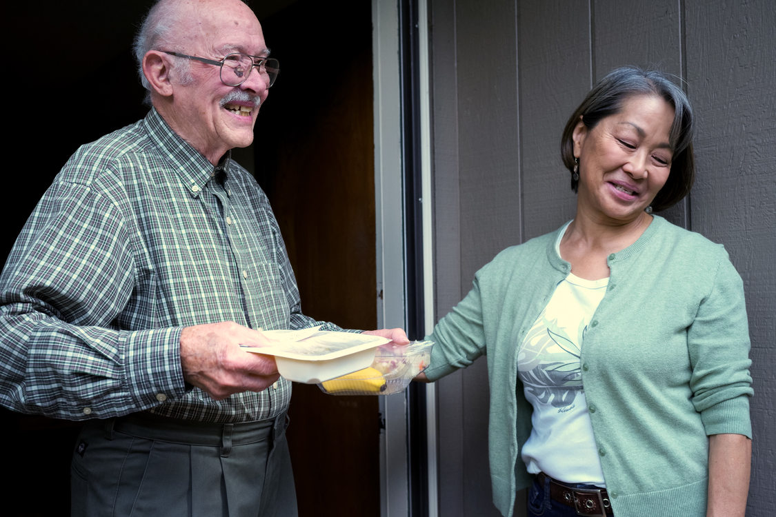 a volunteer delivers a meal to the home of an elderly man