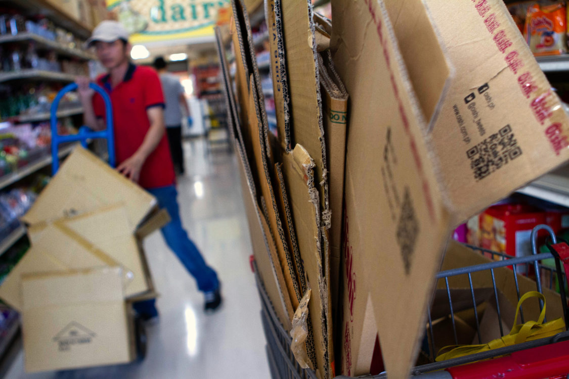 a store worker flattens cardboard boxes