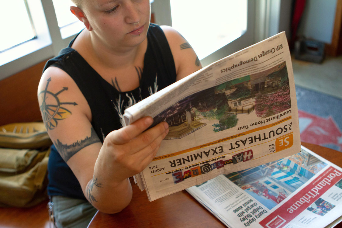 a woman sits in a cafe and reads a newspaper