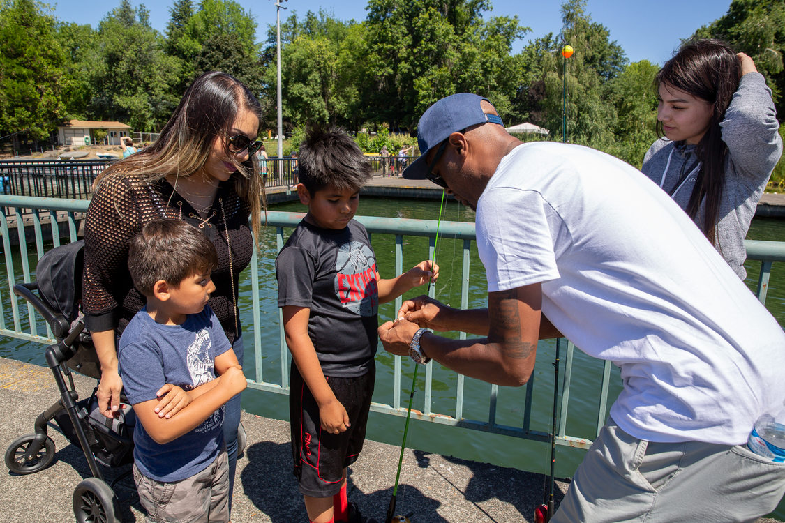 Dishaun Berry of Get Hooked shows a family how to bait their fishing hook at Blue Lake Regional Park.