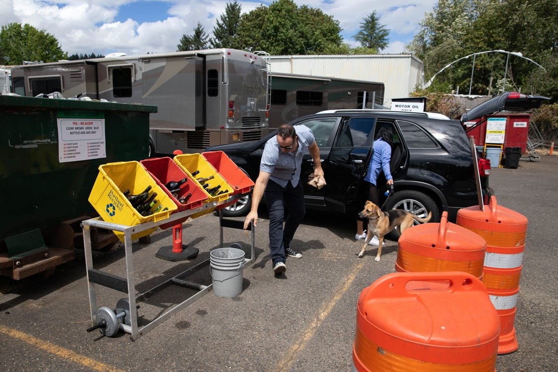 a couple unloads recyclable material from their car