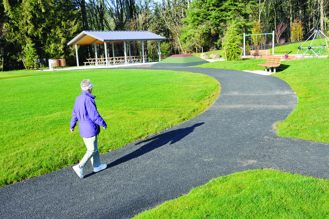 Photo of woman walking on paved path in park