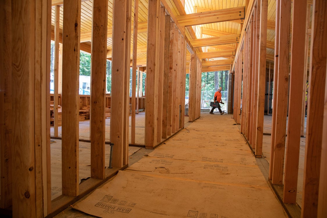 construction worker walks past partially framed building.