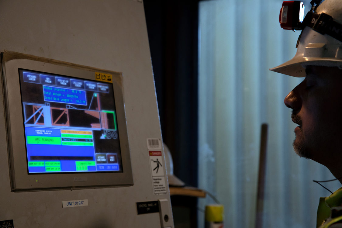 a man in a hard hat monitors a computer screen