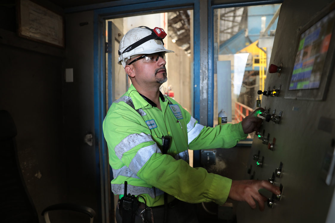 a man in a hard hat monitors a computer screen