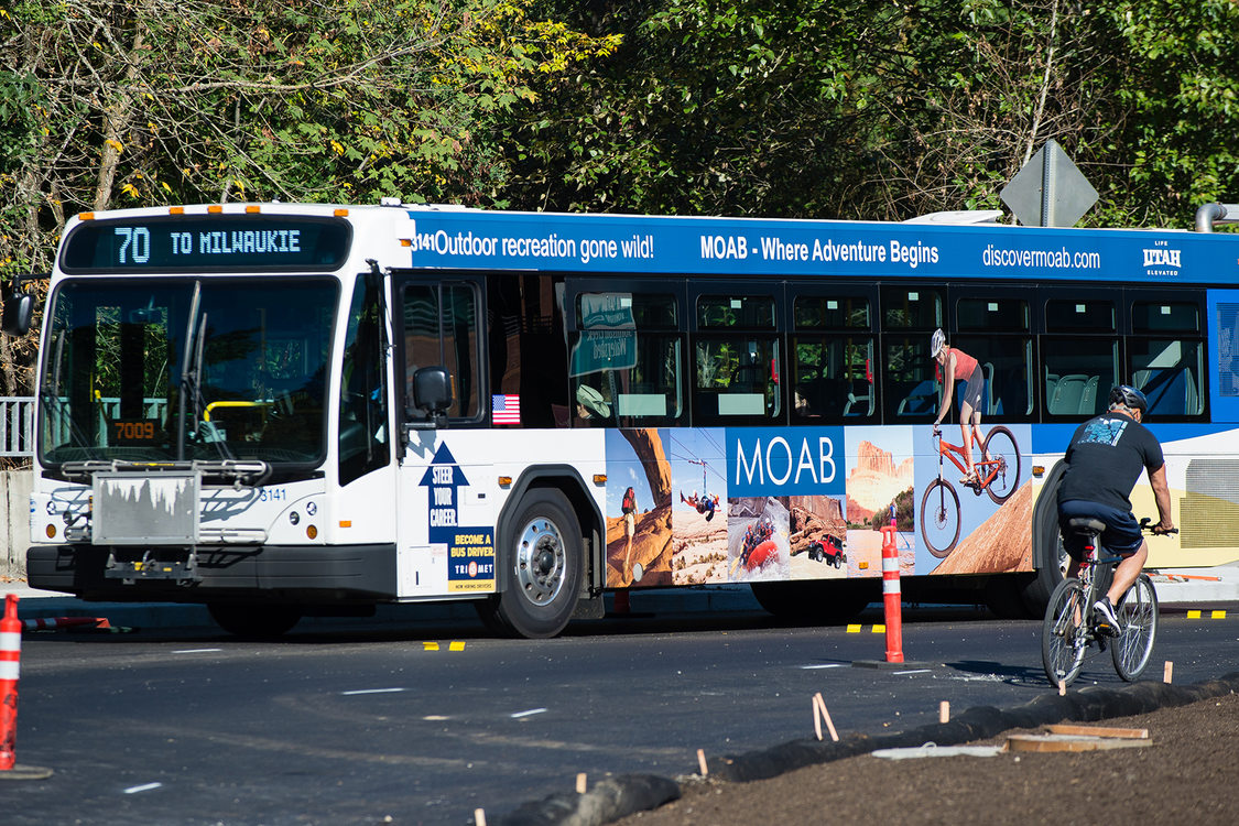 A bus stops next to a man riding a bicycle