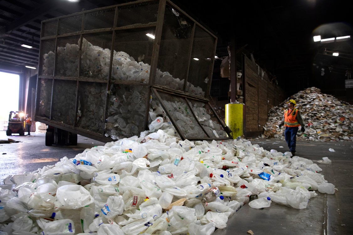 Empty milk containers cover the sorting floor or a materials recovery facility