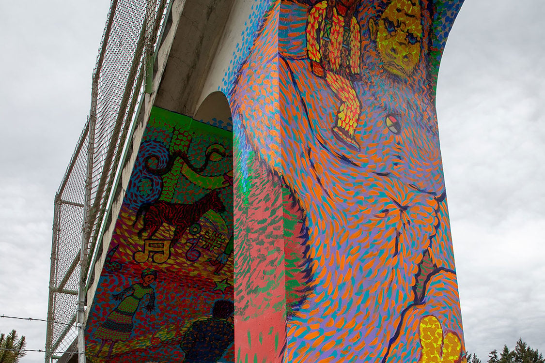 a colorful Bigfoot painted on the column of a pedestrian bridge