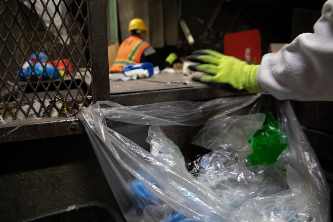 workers on the sorting line pull off plastic bags