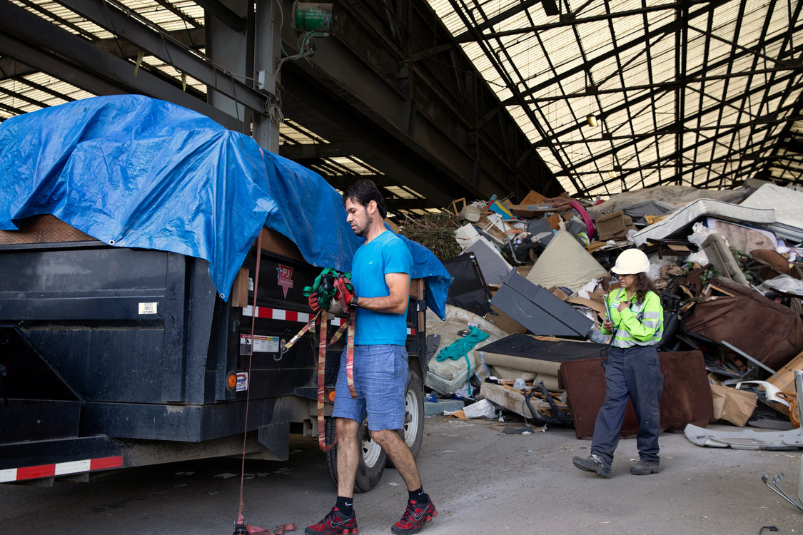 woman in a hard hat inspects a trailer of construction debris