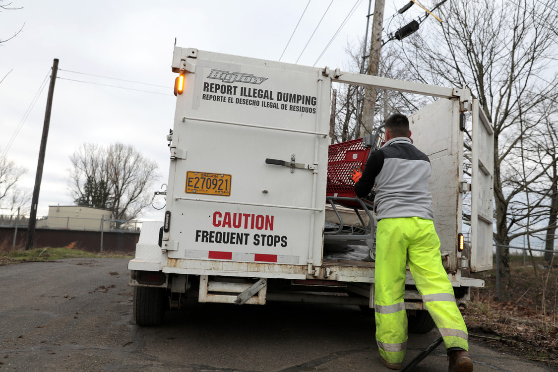 a Metro worker closes the door of the trash trailer behind a RID patrol truck