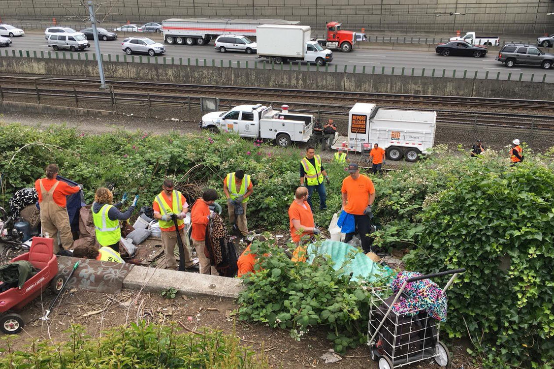 a work crew cleans up a dump site along the highway