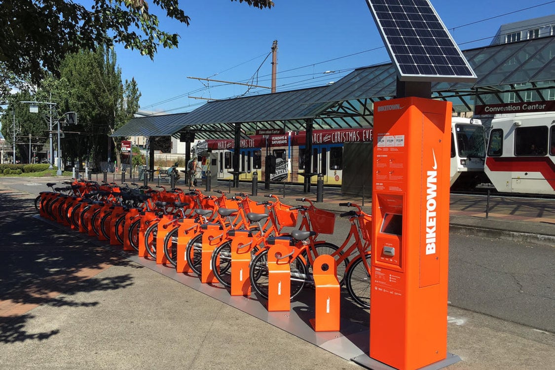 A Biketown station with the MAX light rail train in the background