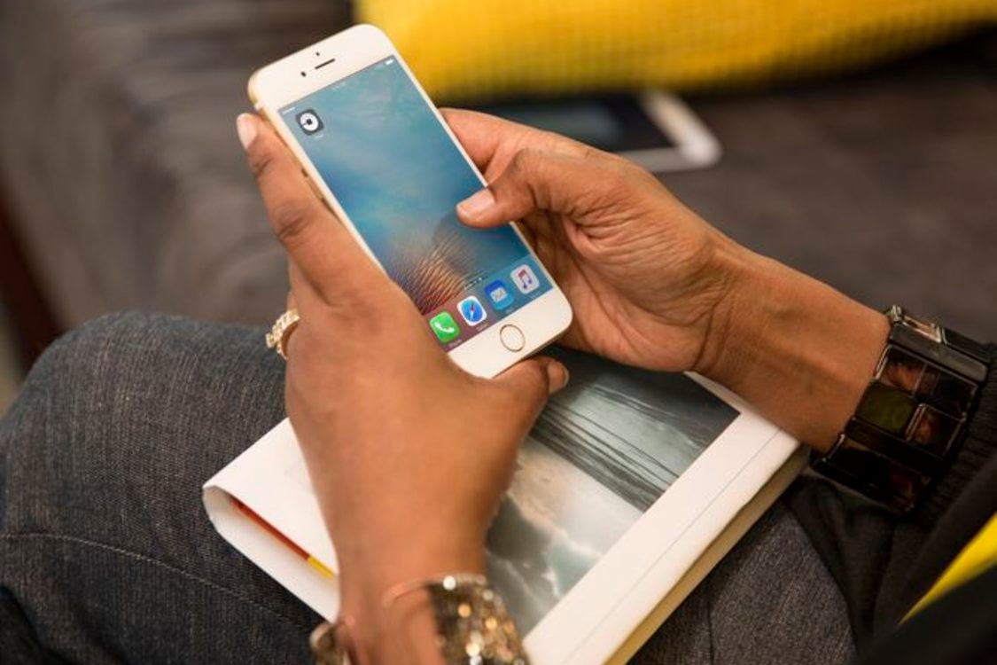 Zoomed in photo of a woman's hands holding a smart phone with a car-hailing app visible from the screen