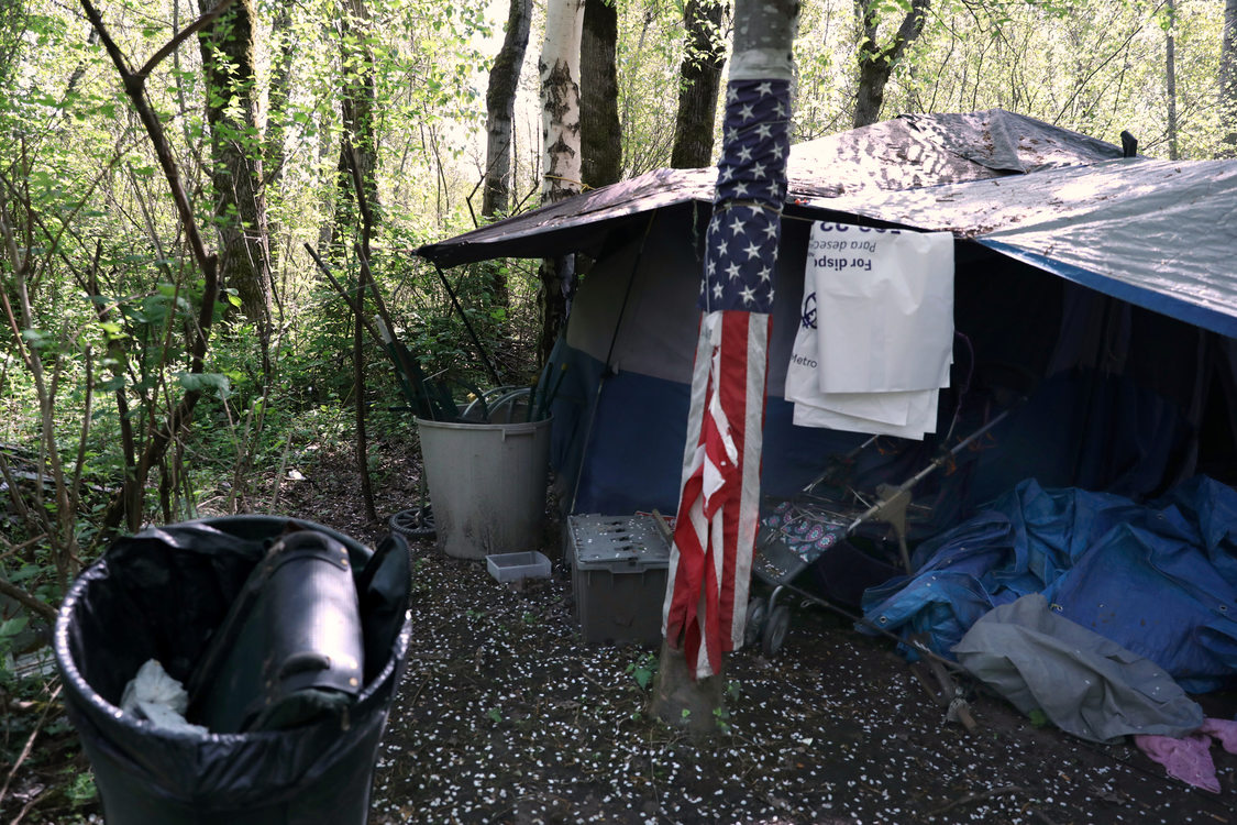 Several Metro bags hang on a line in a campground where the American flag is displayed.