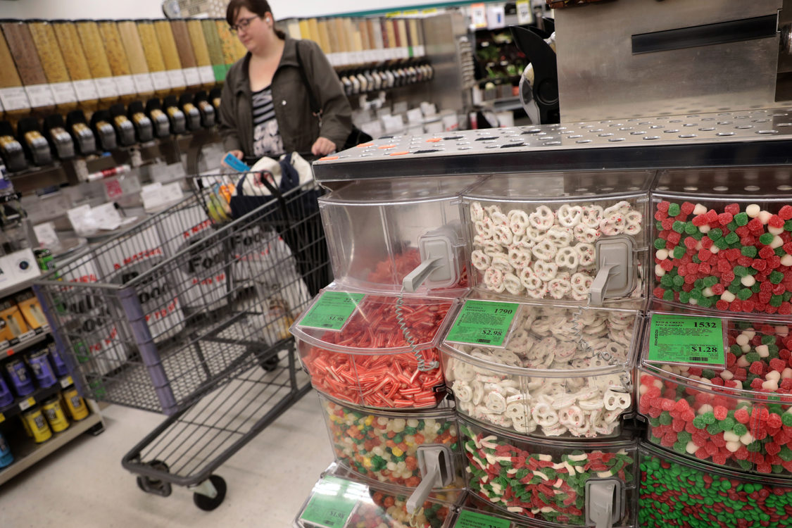 a shopper goes down the bulk isle near bins of seasonal holiday treats