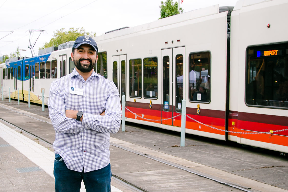 Metro Councilor Juan Carlos Gonzalez standing next to a MAX light rail train