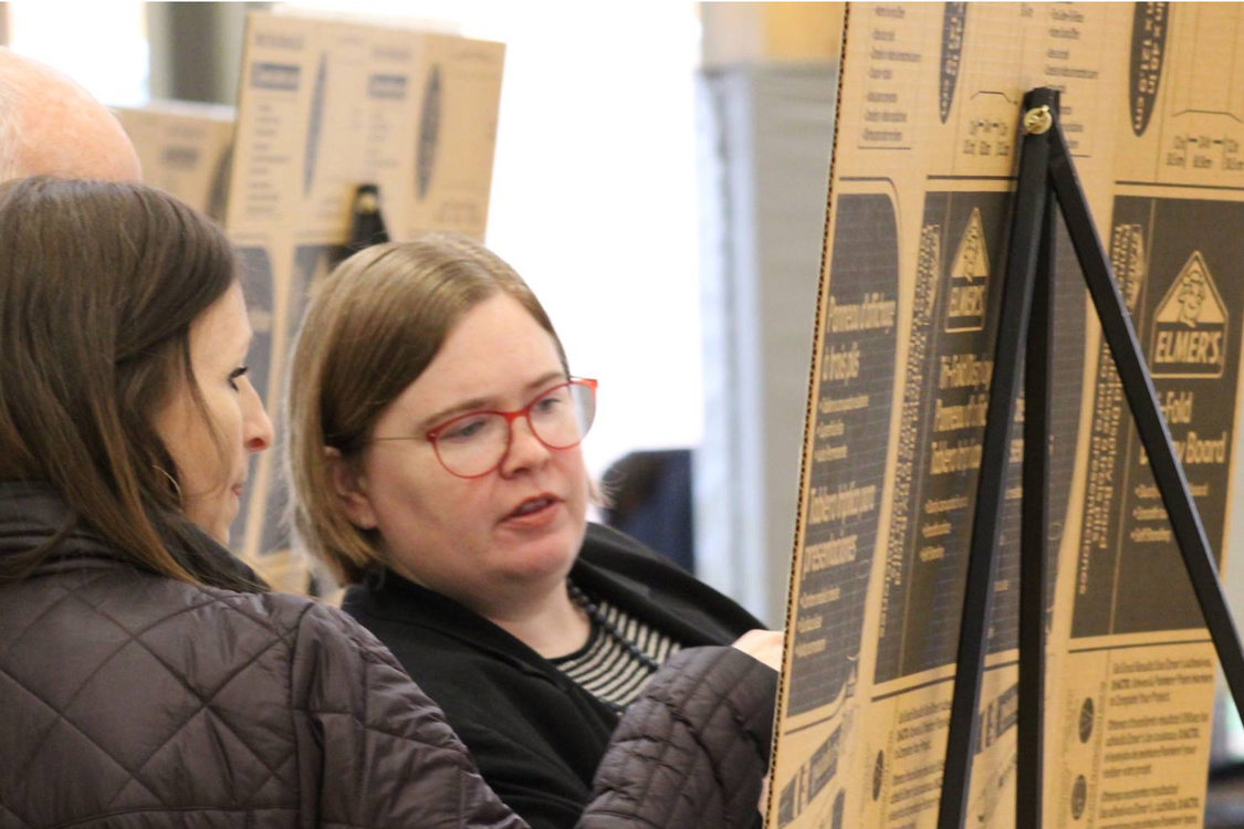 Metro Councilor Christine Lewis reviews presentation material on a cardboard easel with a member of the public