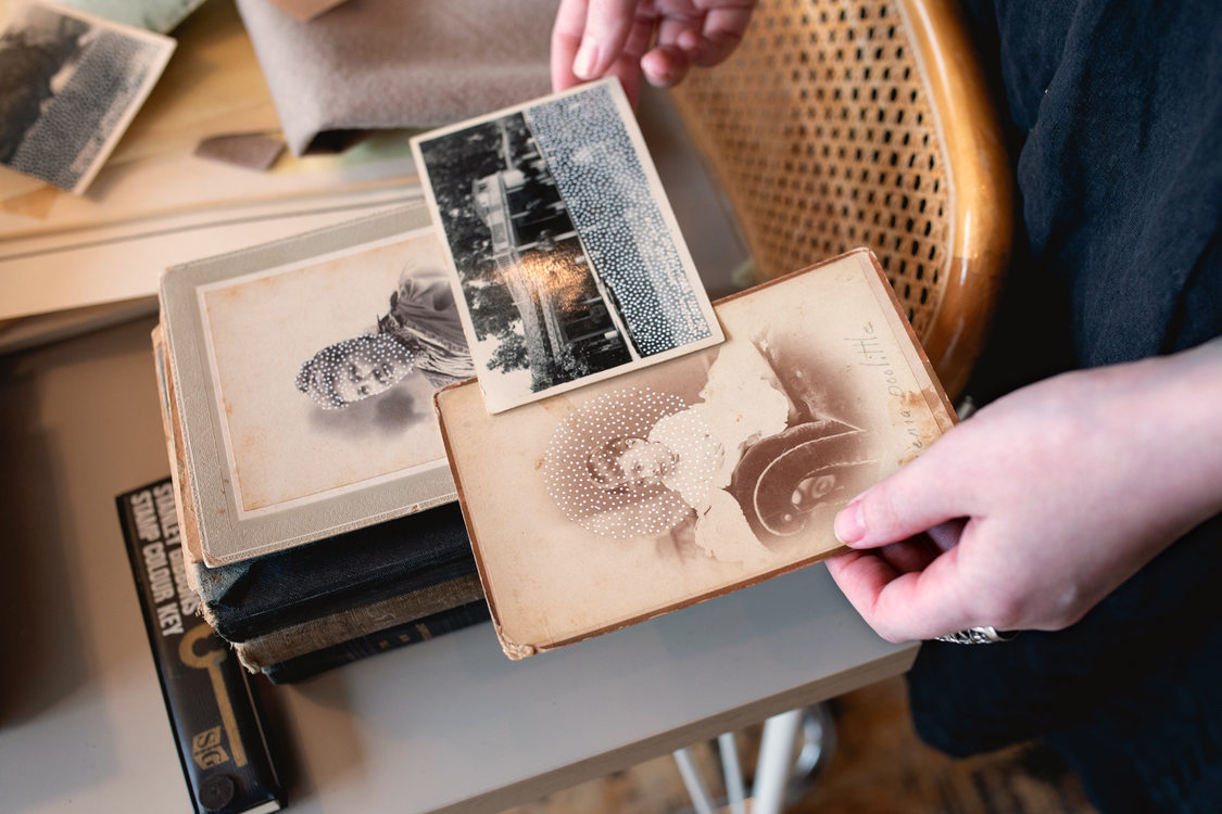 An artist holds turn-of-the-century family photos that she has embellished with paint 