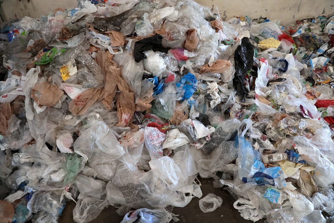 a pile plastic bags and film letters the floor of a materials sorting facility