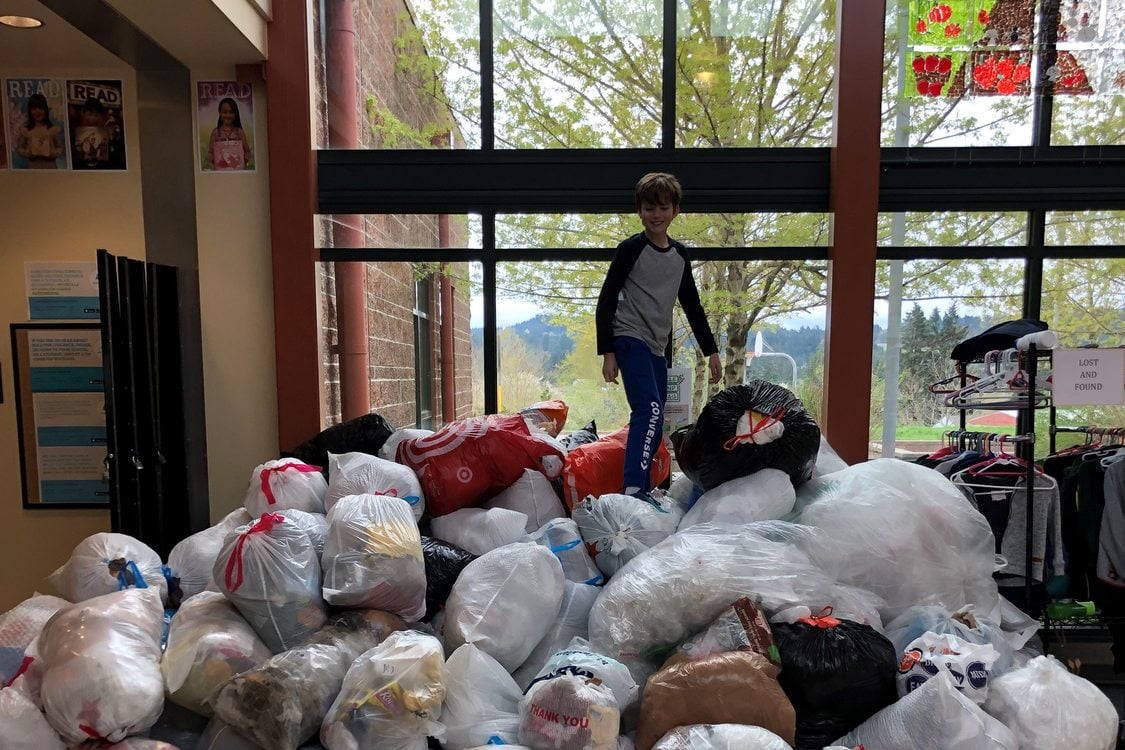 A child stands on top of plastic bags collected for recycling.