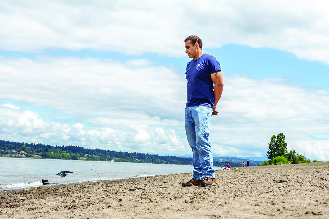 A man looks at two blackbirds on a river bank.