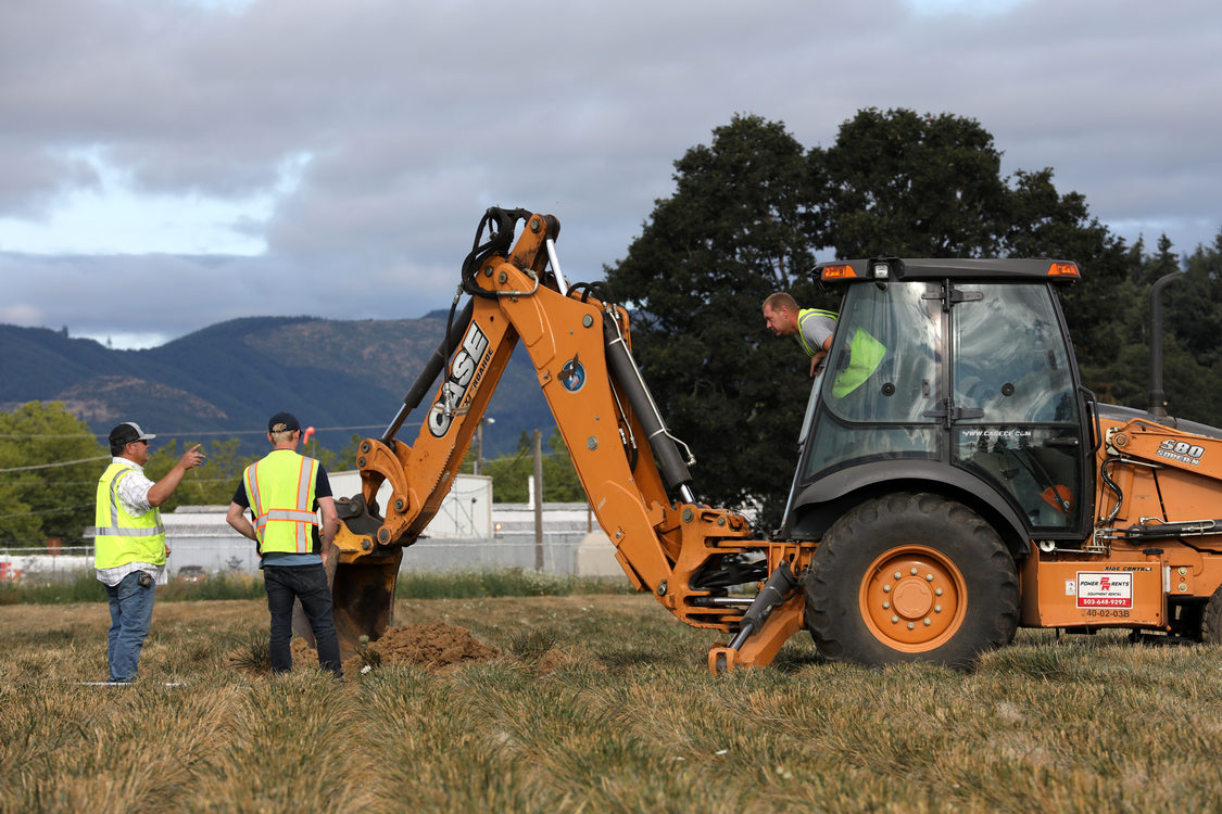 A tractor operator leans out of his tractor cab to converse with two co-workrs at a test site in rural  Washington County.