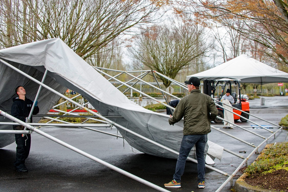 A crew sets up tents for a drive through COVID-19 testing site