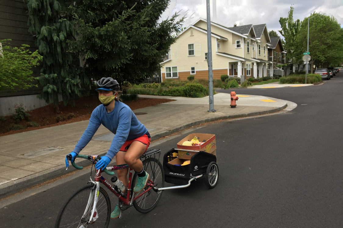 A person biking while hauling a trailer with boxes of food for delivery