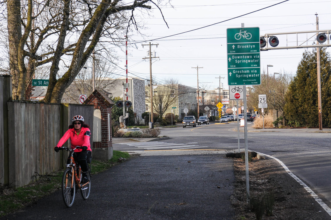 A cyclist rides on a dedicated trail alongside a street in southeast Portland