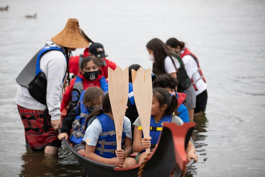 Portland All Nations Canoe Family pull in a canoe with youth and elders to shore