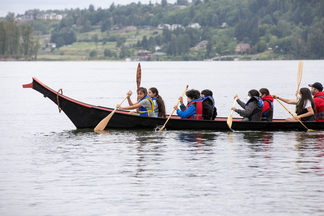 a group of young people rowing in a canoe in the Columbia River