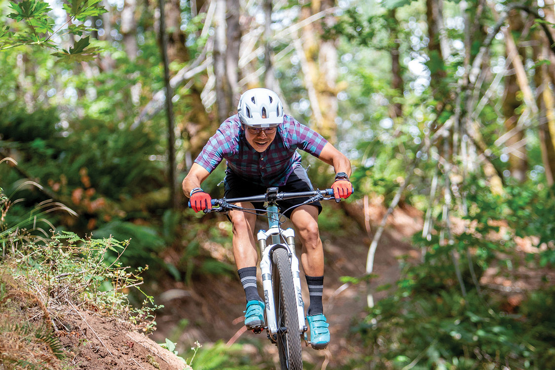 A mountain biker jumps over a small mound on a dirt path in Newell Creek Canyon Nature Park.