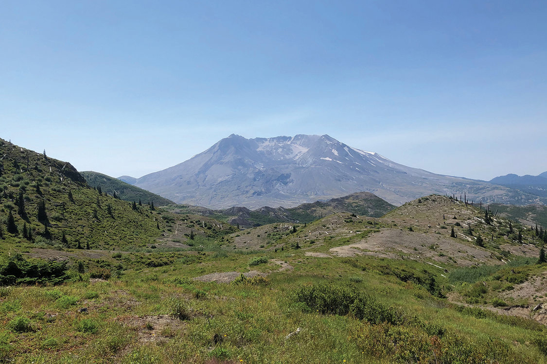 The hollow caldera of Mt. Saint Helens towers over the prairies and meadows around the volcano.