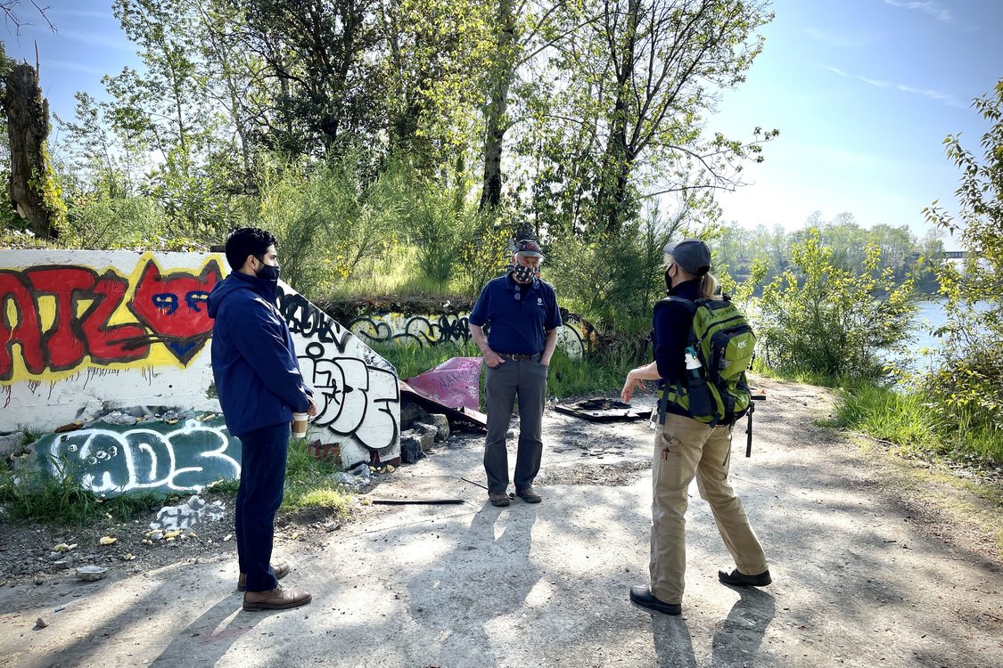 Metro Councilor Gerritt Rosenthal speaks with fellow Councilor Juan Carlos Gonzalez and Metro scientist Katy Weil next to a graffiti-covered wall along the banks of the Willamette River