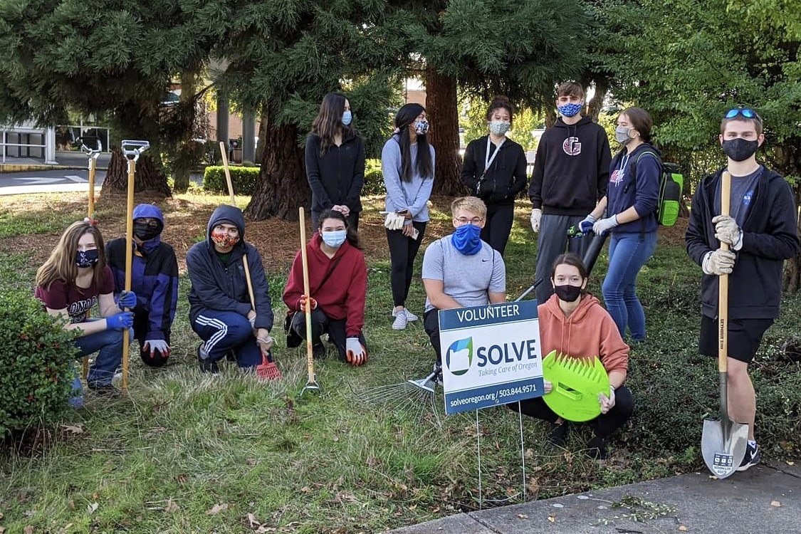 An image of volunteers with garden tools standing behind a SOLVE sign