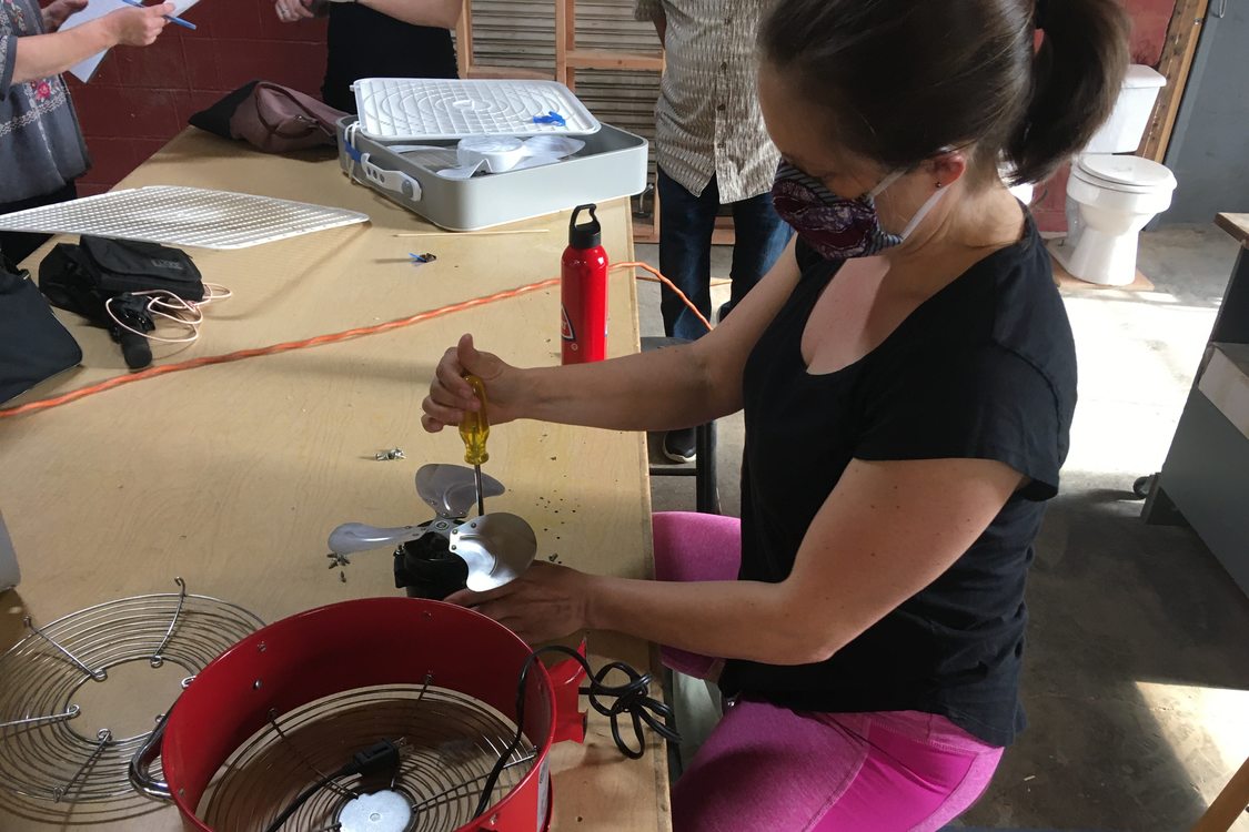 An image of a woman repairing a red fan