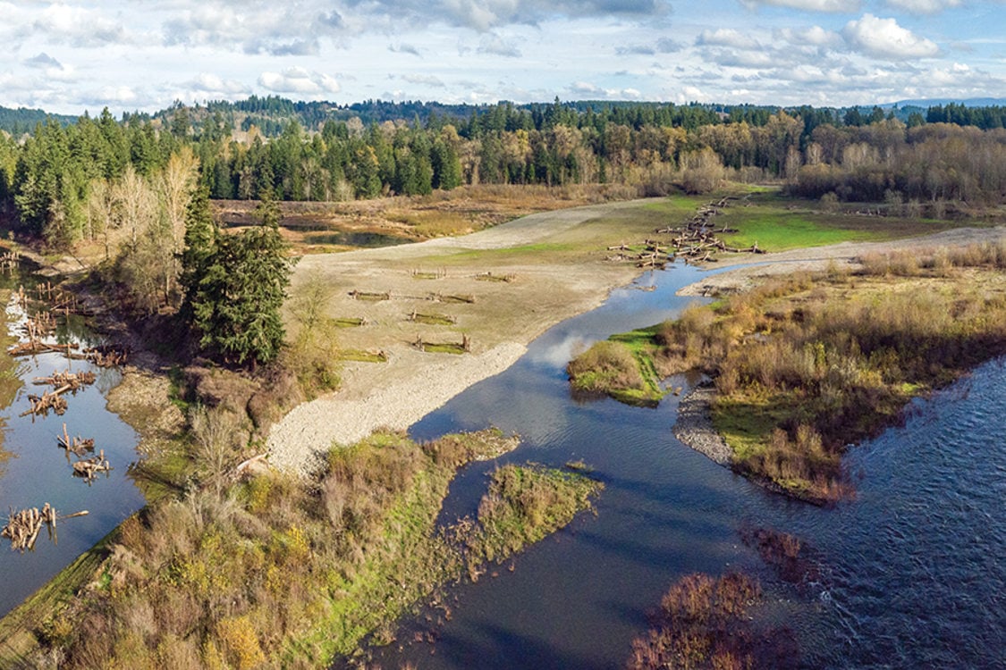 A large river wraps around a natural area that is mostly brown with few plants.