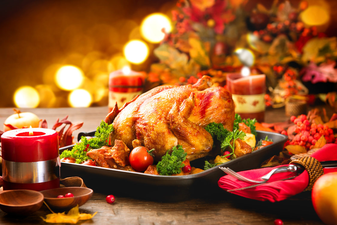 Image of a holiday dinner table featuring a roasted turkey and candles