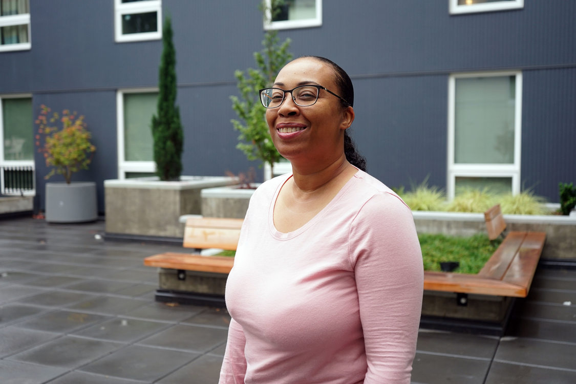 Woman in pink blouse standing in outdoor courtyard