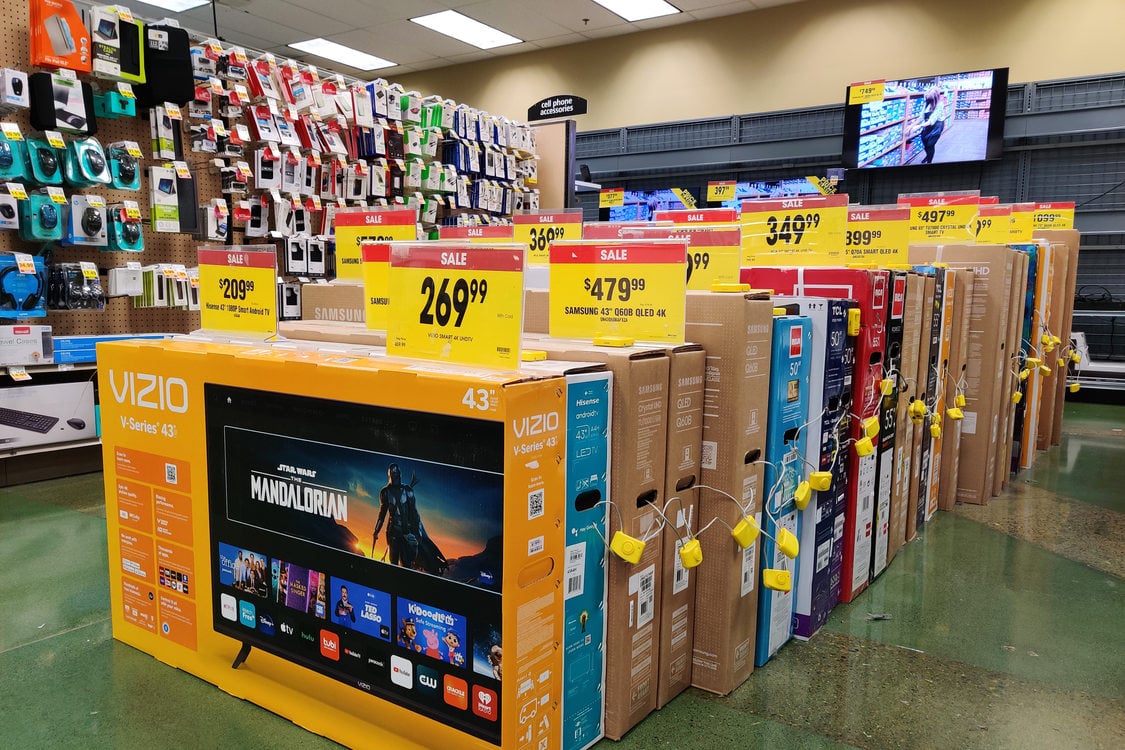 18 boxes of new televisions on a sales floor. Each TV has a bright yellow price tag with the sale price