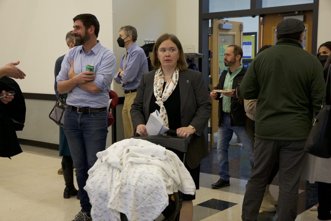 In a crowd of people, Metro Councilor Christine Lewis pushes a stroller.