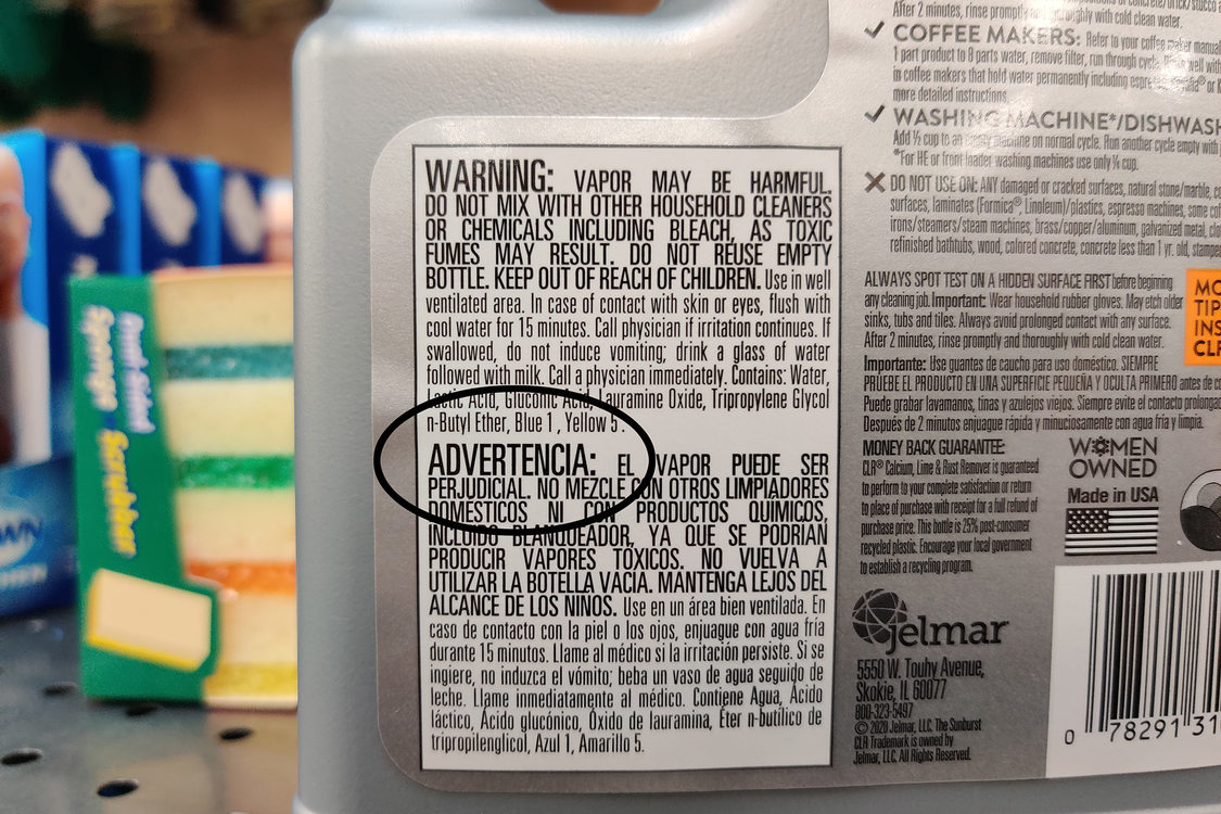 The bottom half of a silver bottle of cleaner with a white label that reads WARNING on the back