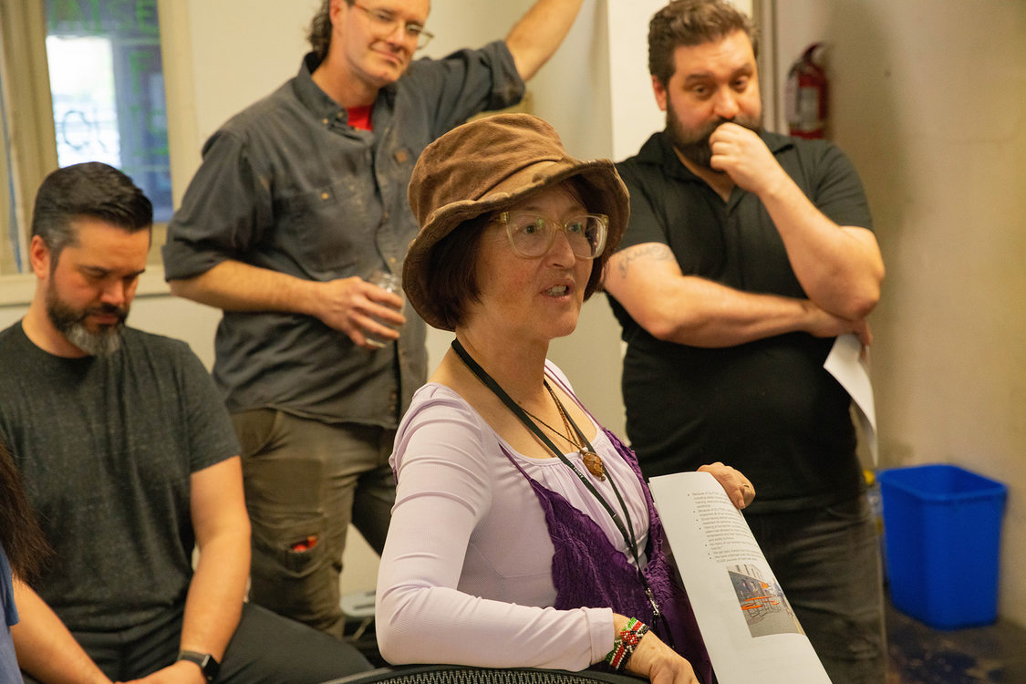 Four people with the focus on a woman in front who is holding a flyer about the program she co-founded 