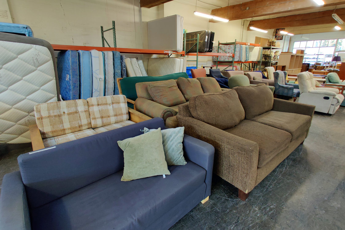 interior of a warehouse with couches in the foreground and mattresses in the back